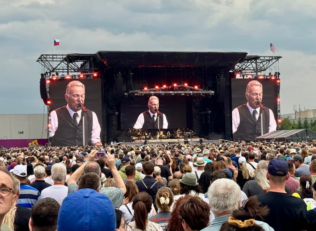 A huge outdoor concert with Bruce Springsteen on three big screens on stage.