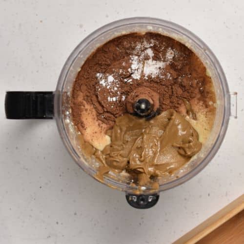 Adding other Flourless Protein Cake ingredients to the food processor.