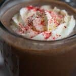 Titled image close up of a keto peppermint mocha with whipped cream and red sprinkles on top.