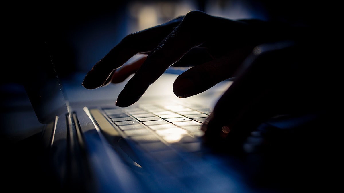 Someone typing on a computer in a dark room.