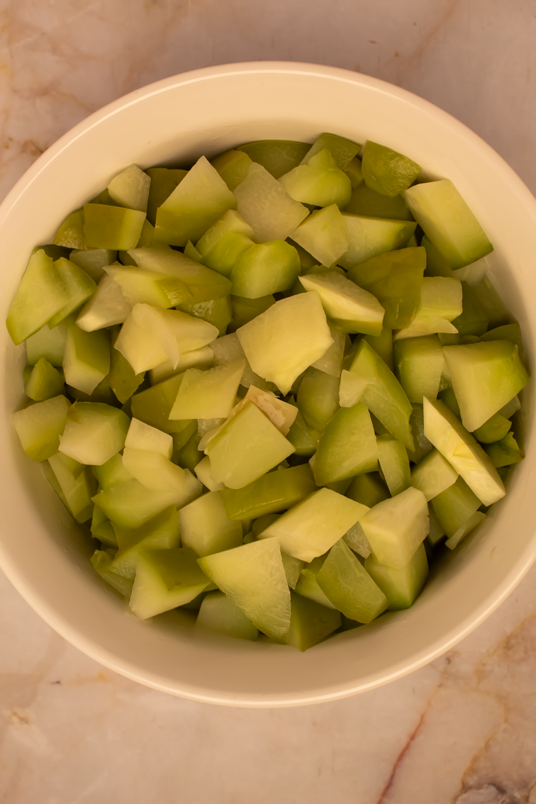 Chopped squash in a round white bowl. 