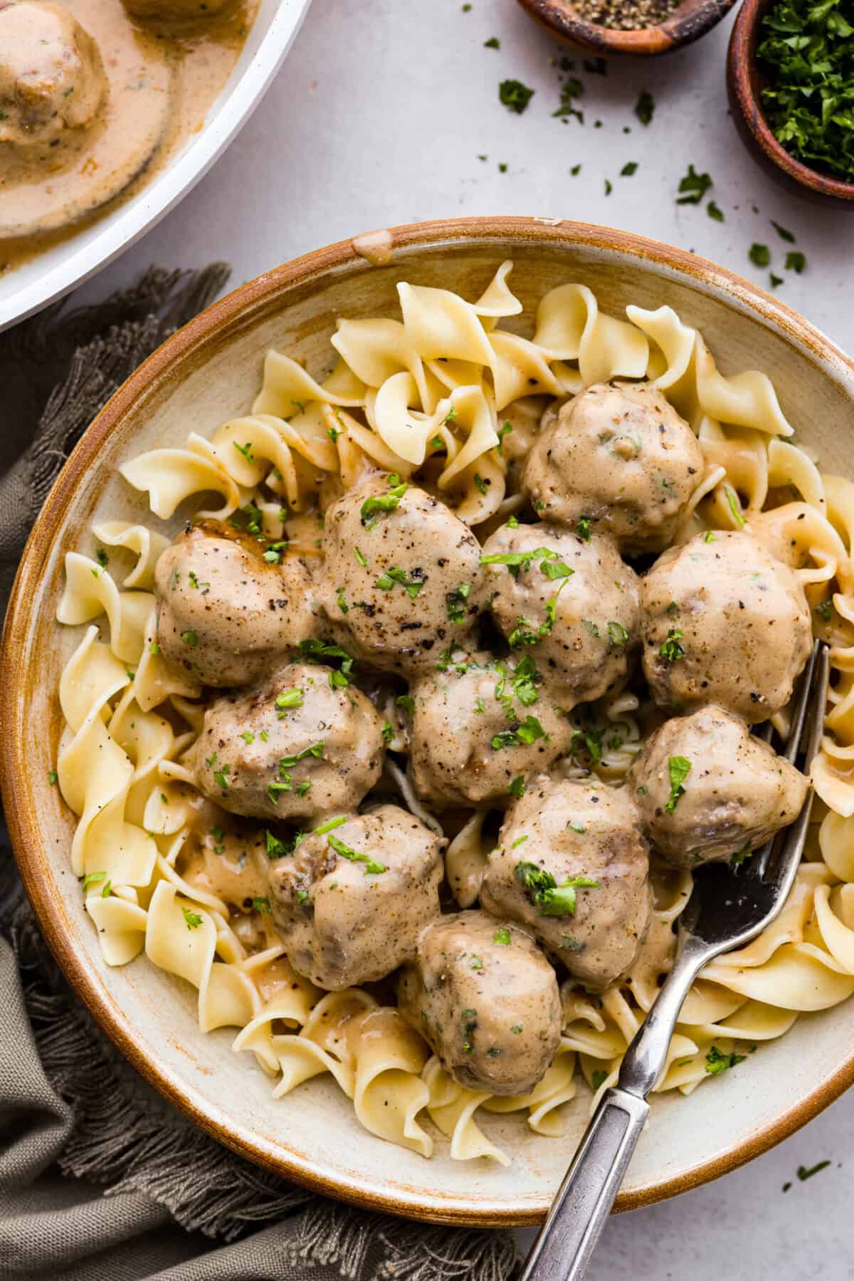 These Swedish Meatballs are smothered in the most amazing rich and creamy gravy and packed with such delicious flavor. You will quickly agree these are the BEST you have ever had! Swedish meatballs on top of egg noodles in a bowl.