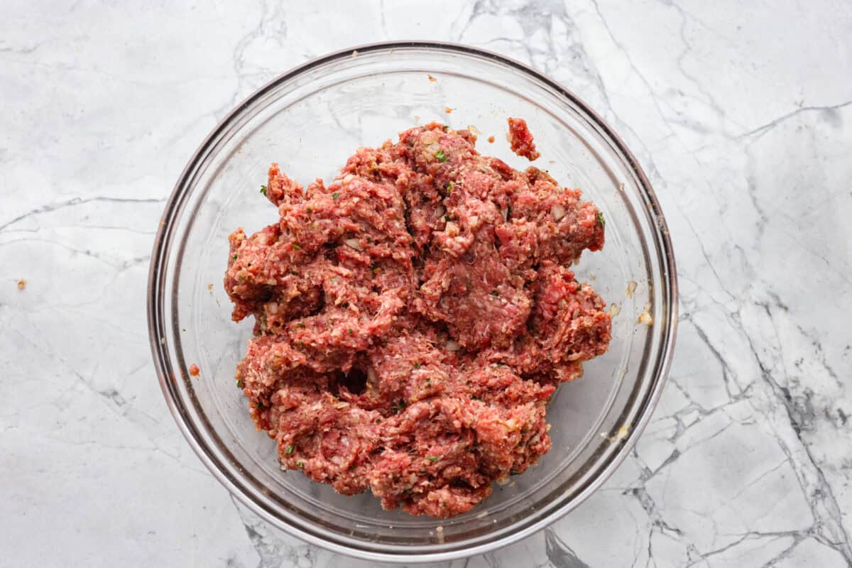 These Swedish Meatballs are smothered in the most amazing rich and creamy gravy and packed with such delicious flavor. You will quickly agree these are the BEST you have ever had! Ground beef and spices combined in a glass bowl.
