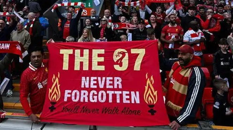 Getty Images Liverpool fans at a football game hold a flag which reads 'The 97 Never Forgotten'.
