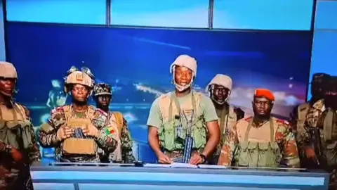 BTV Screengrab of soldiers talking on national TV in Benin. They are in fatigues, some with guns.