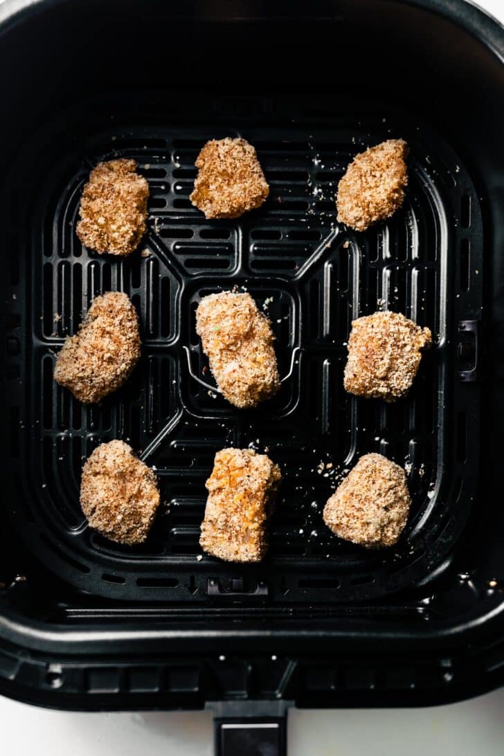 Breaded chicken nuggets in an air fryer basket before cooking