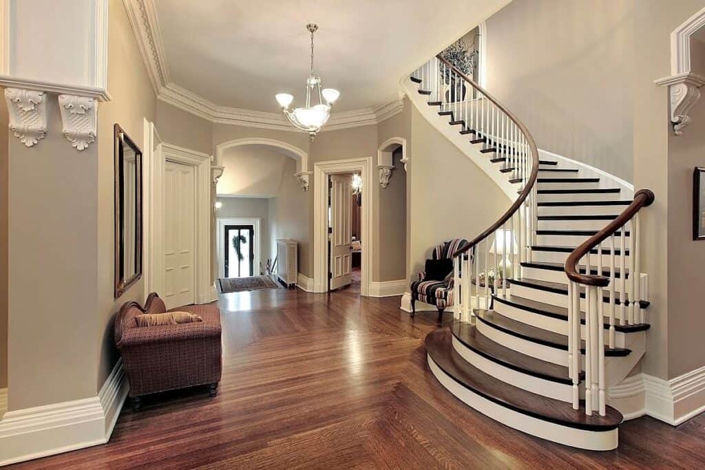 Elegant entrance hall with curved staircase, wooden floors and statement lighting, showing how a well presented hallway can increase home value.