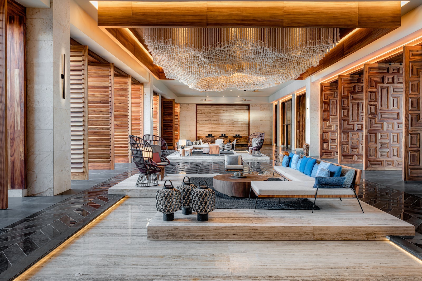 large room with wooden doors, couches and chairs, hanging rope art