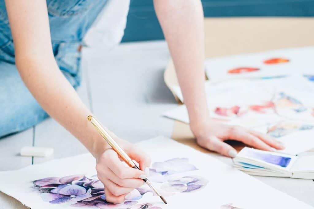Person painting flowers as a creative hobby for wellbeing.