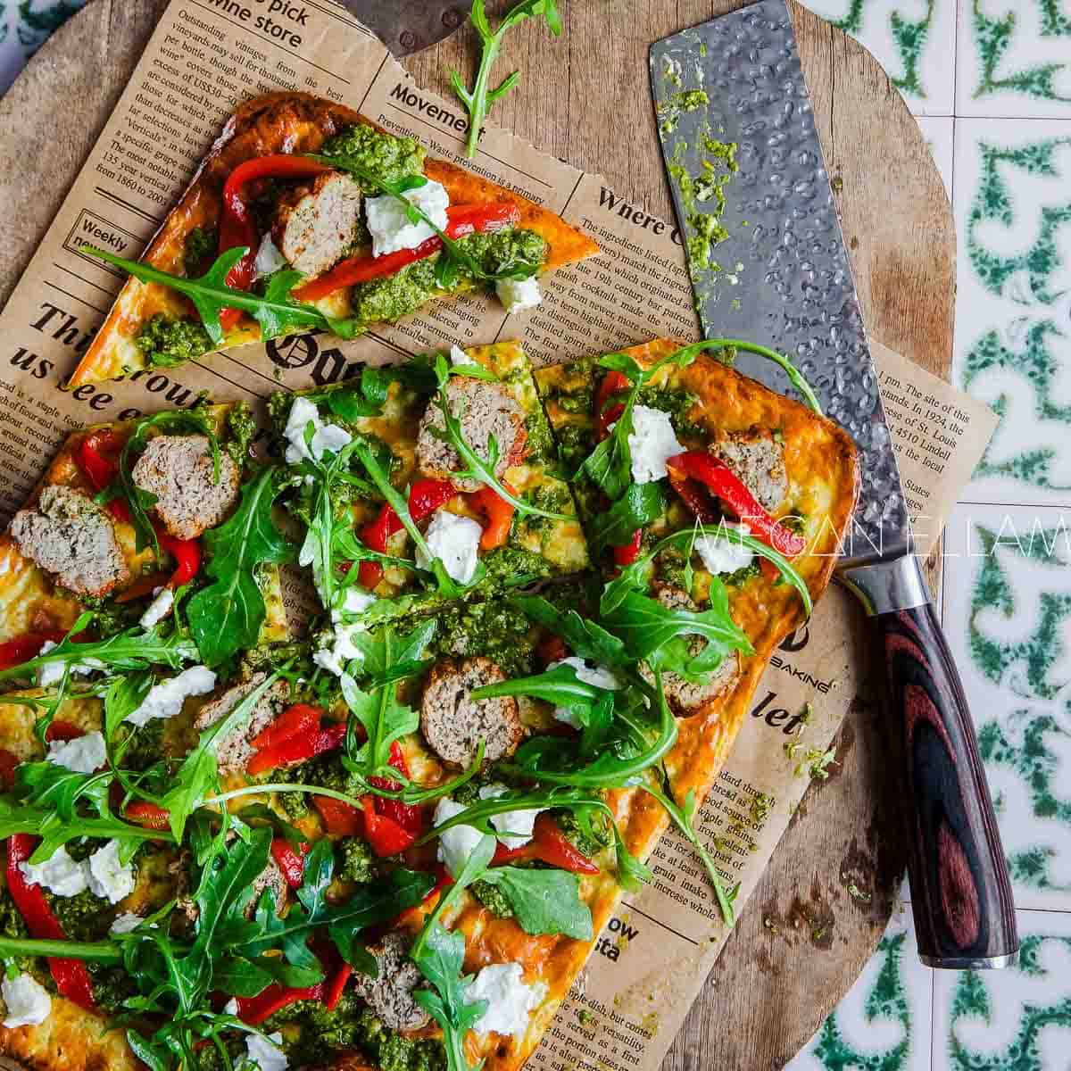 Cottage Cheese Flatbread pizza topped with sausage and rocket.