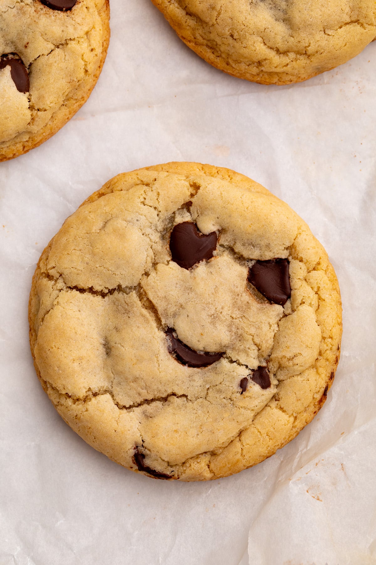 Close-up of a baked chocolate chip cookie on parchment paper.
