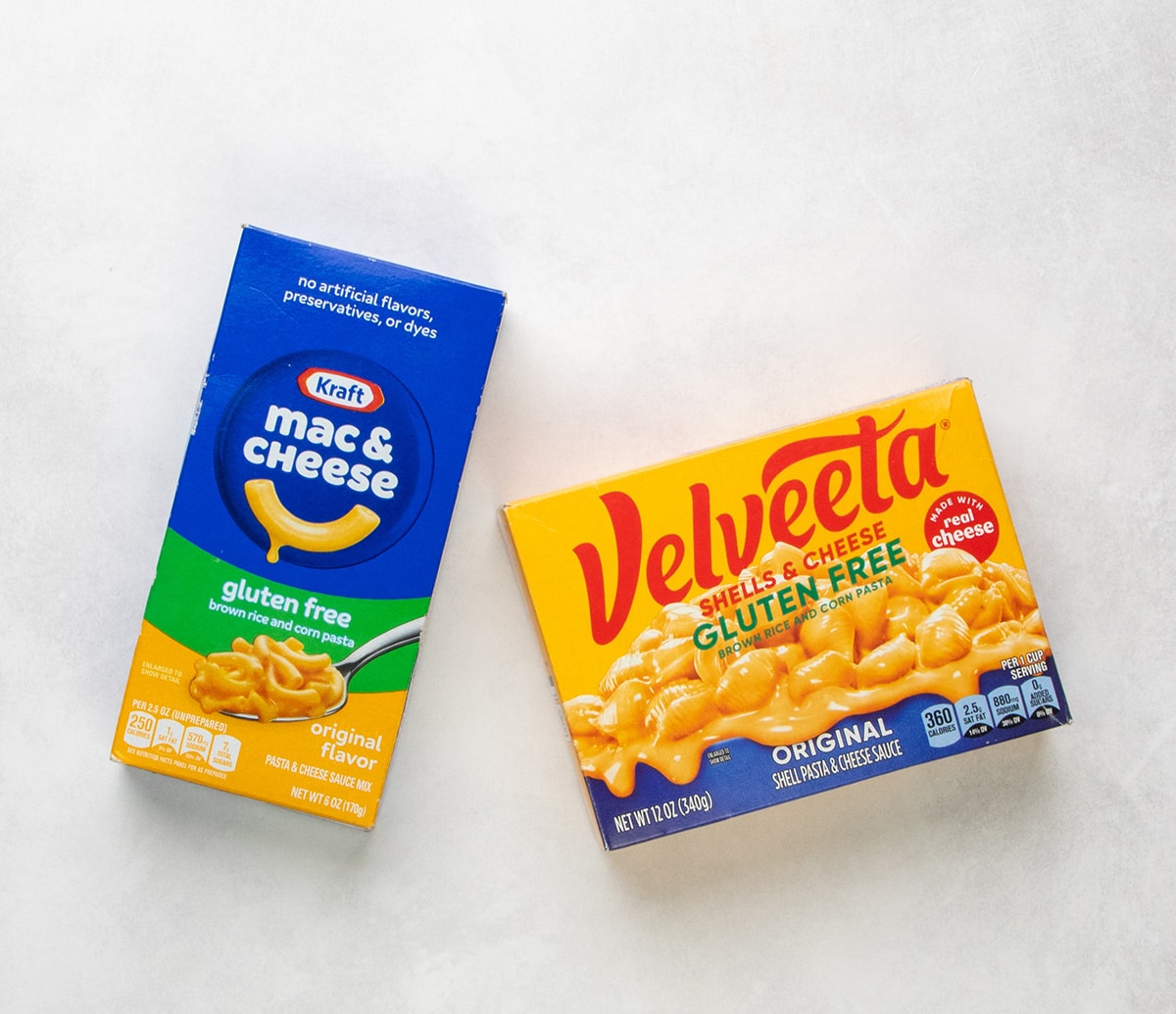 A box of Kraft gluten free macaroni and cheese next to a box of Velveeta gluten free shells and cheese.