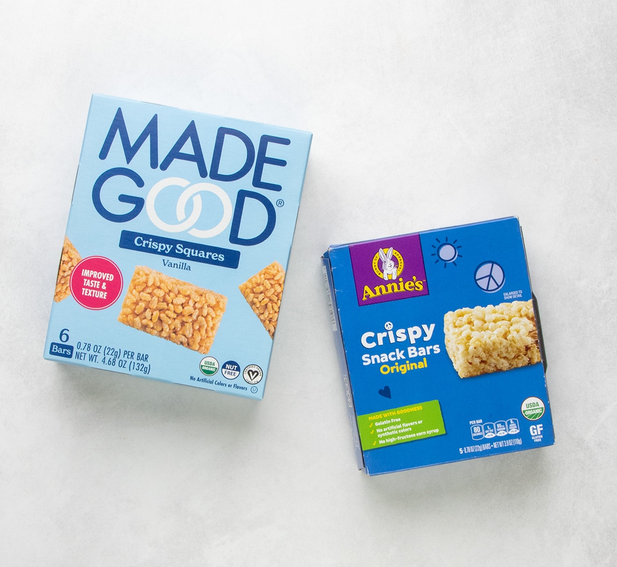 Boxes of MadeGood crispy squares and Annie’s crispy snack bars on a light surface.