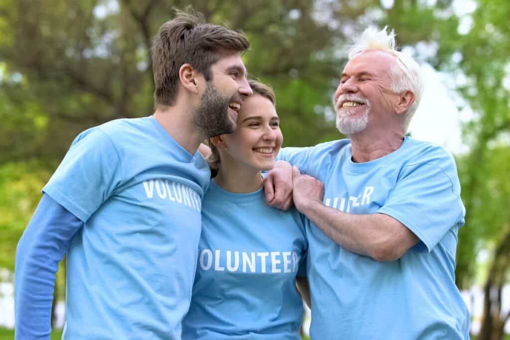 Volunteers smiling together outdoors in matching blue shirts.