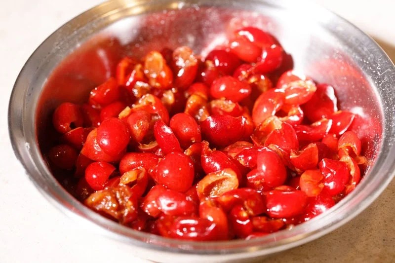 Halved fresh red cherries in a bowl.