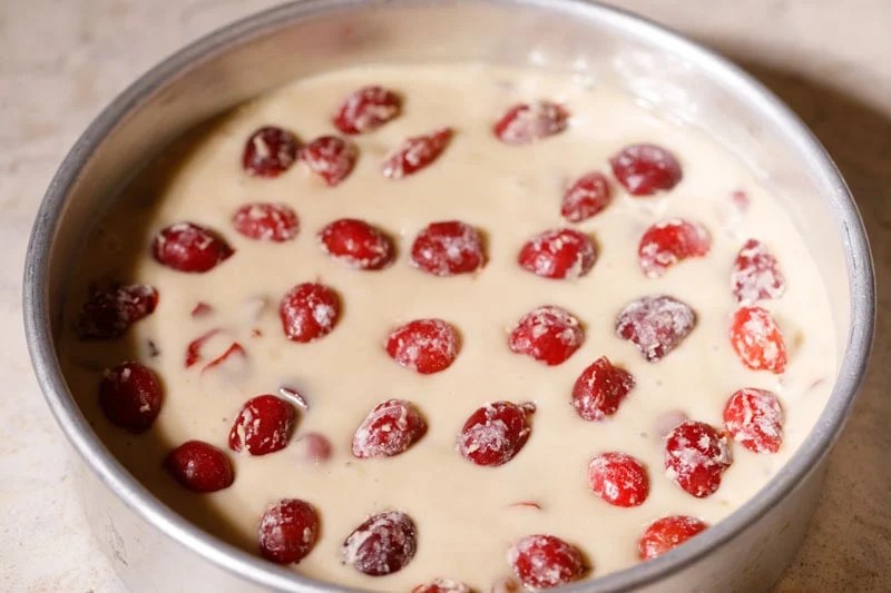 Halved cherries placed on top of cake batter.