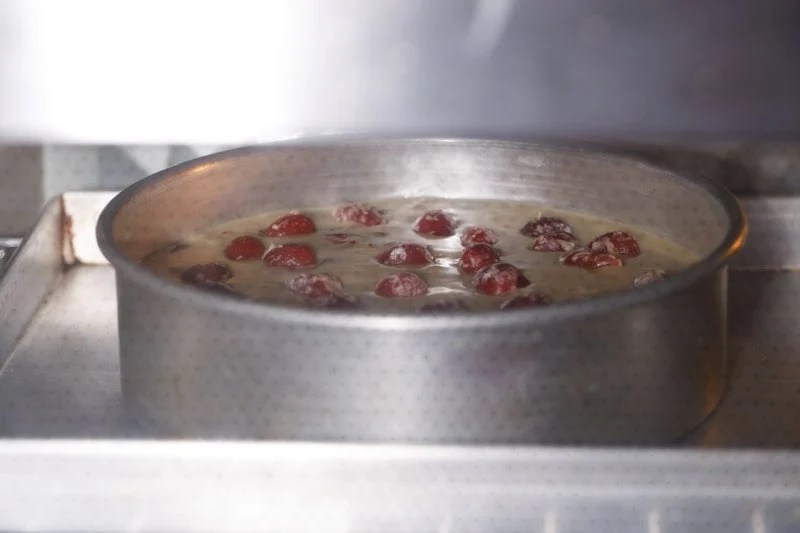 Baking pan with cherry cake batter in the oven.