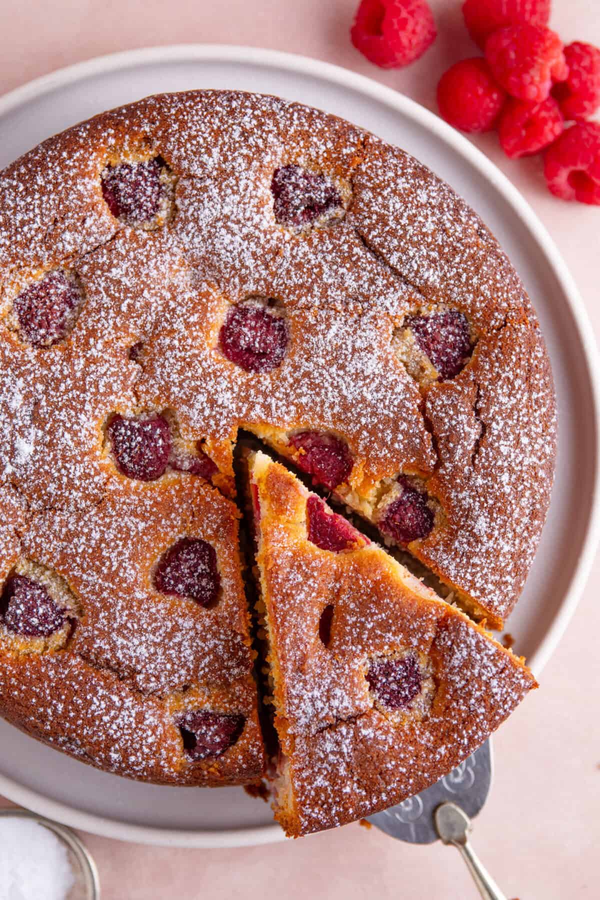 Overhead shot of a gluten free ricotta and raspberry cake with a slice cut out.