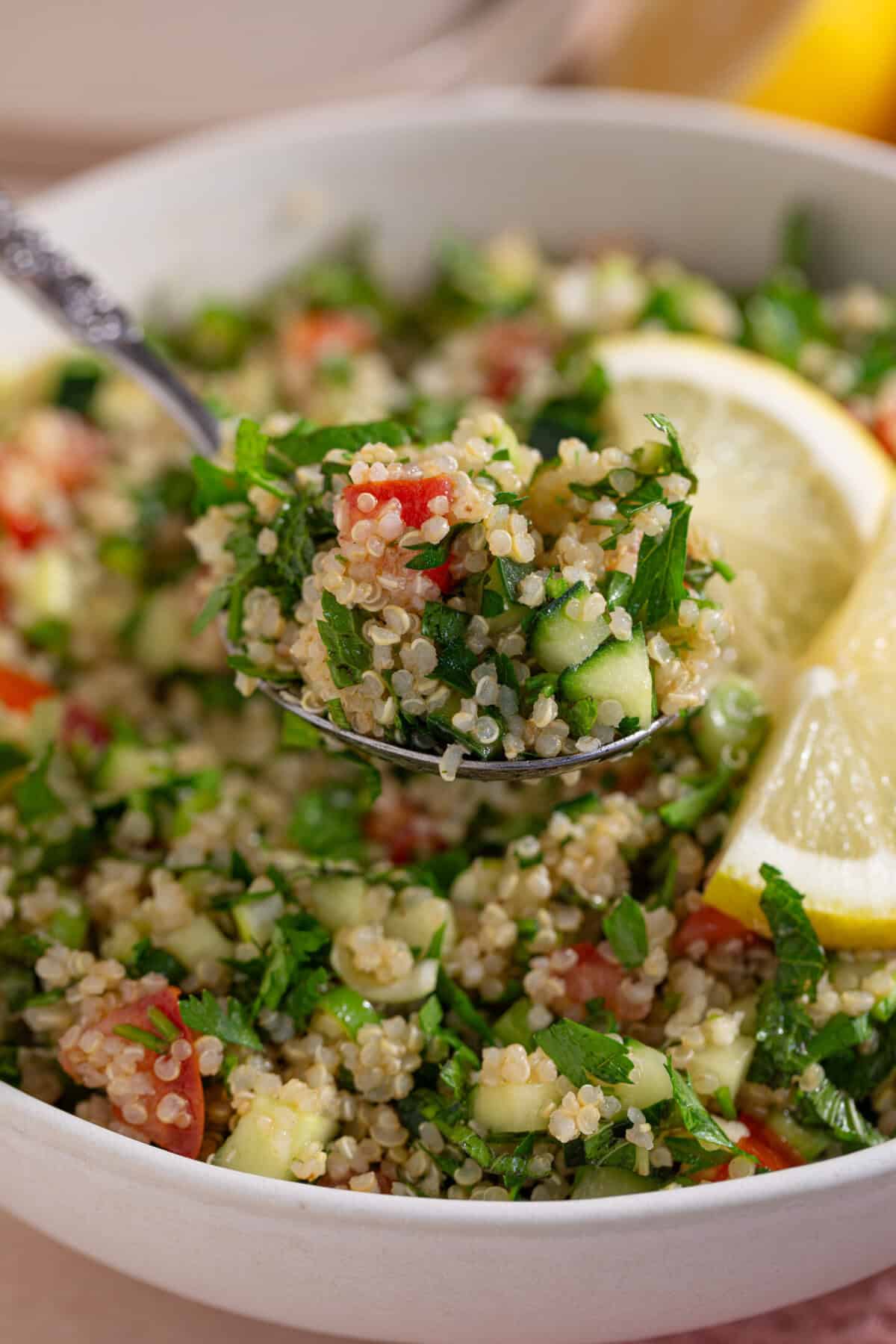 A spoon lifting out a portion of gluten free tabbouleh from a bowl.