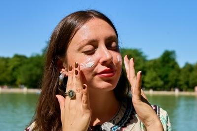Young woman using sun protection cream in sunny warm weather