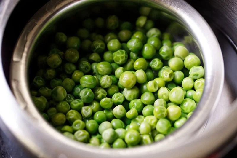 Steamed green peas in cooker in bowl.