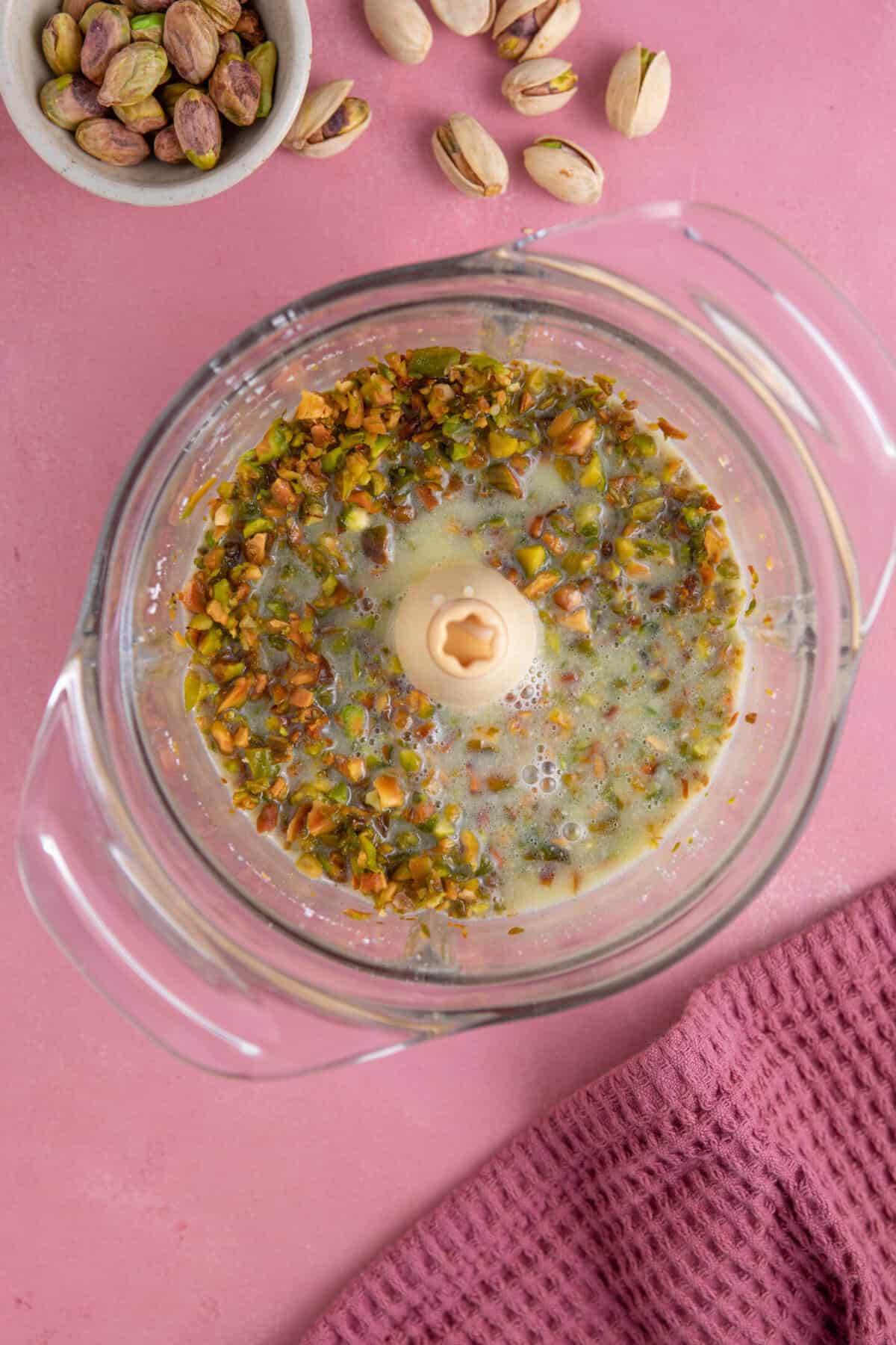 Process shot for pistachio spread recipe showing the milk mixture added to the blender with the nuts.