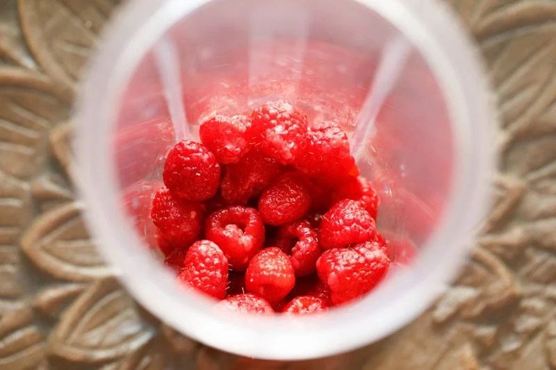Fresh raspberries in a blender cup.