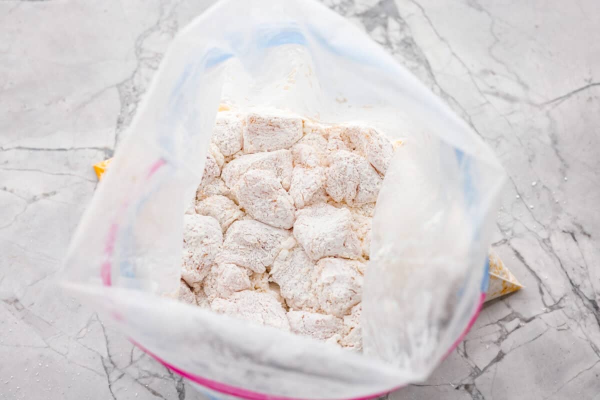 Looking down in to an open ziplock back with cornstarch and chicken pieces. 