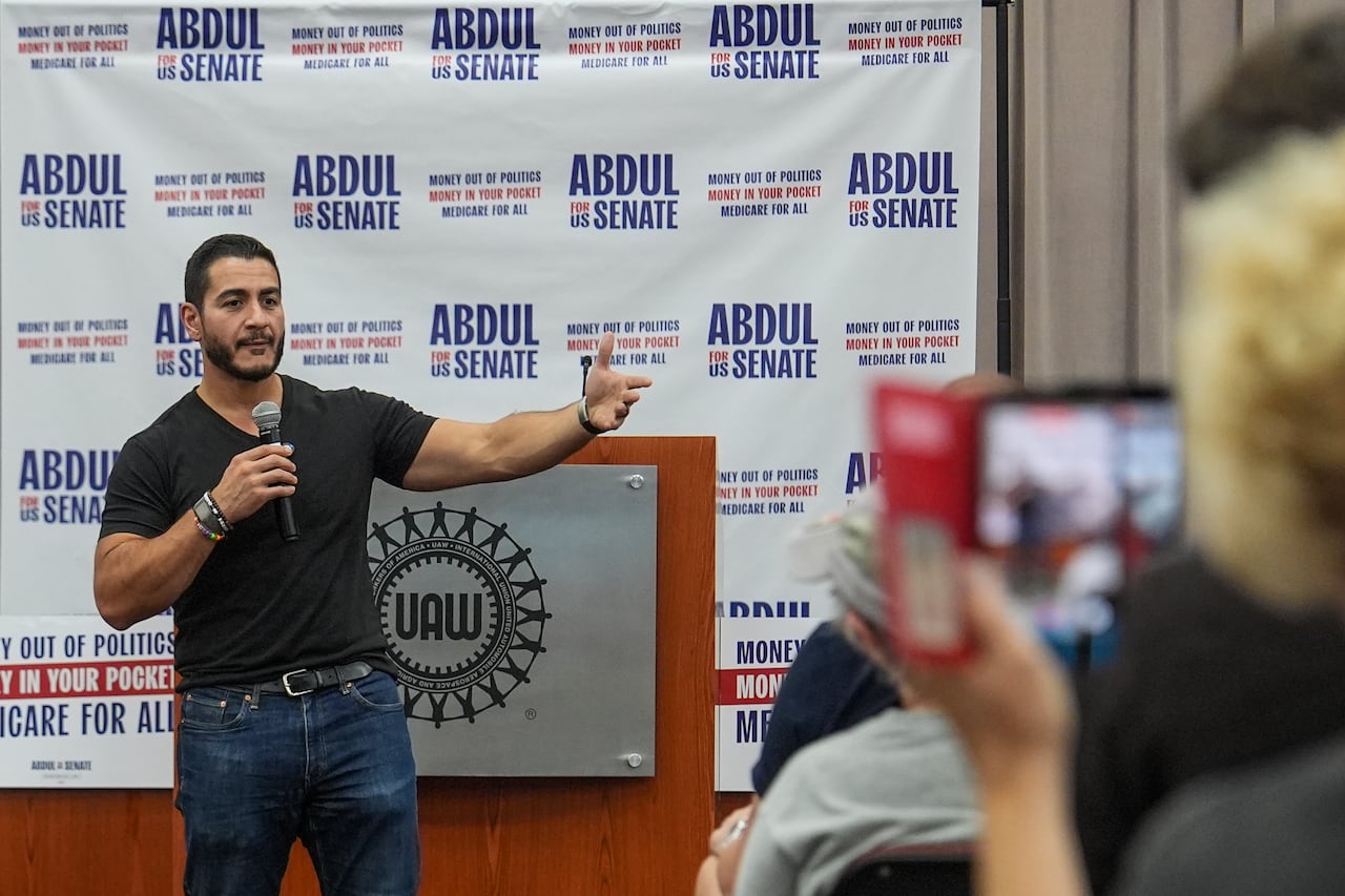 A man gestures while standing in front of a podium