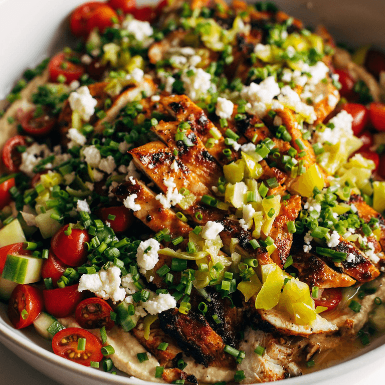 Grilled chicken in a bowl with hummus.