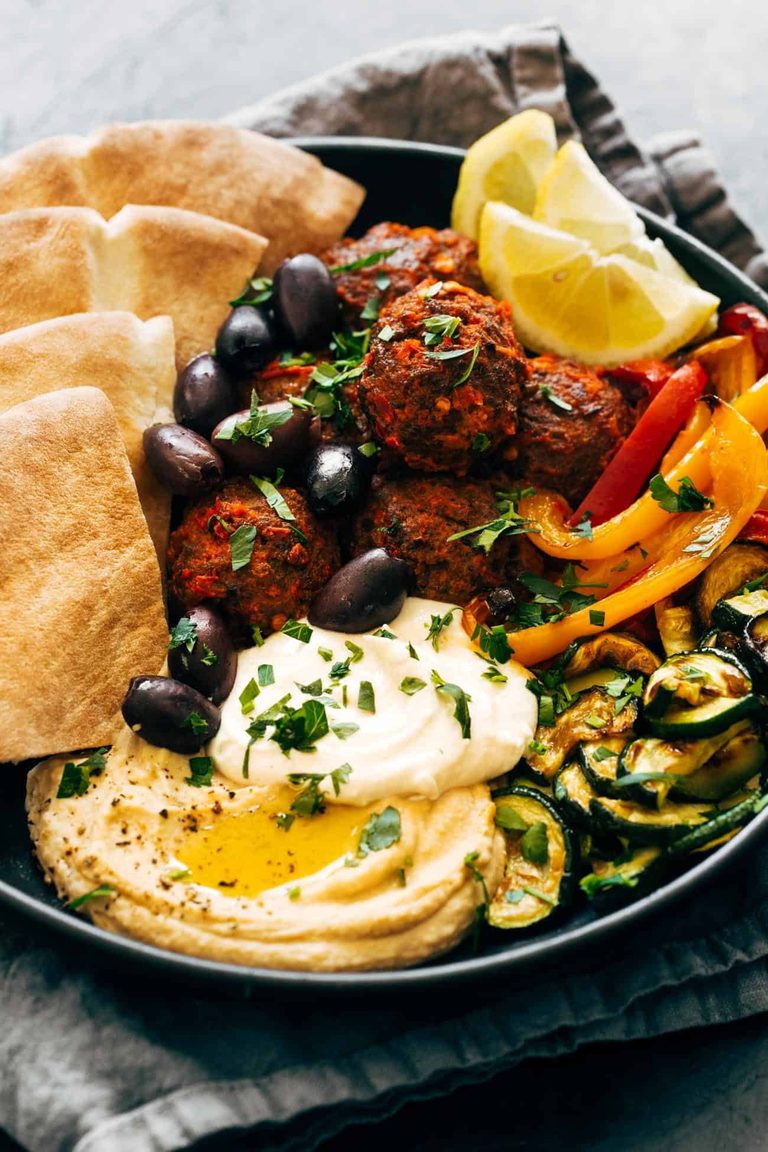 Harissa meatballs on a plate with veggies and pita.