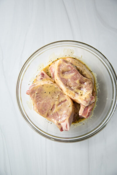 boneless pork loin chops marinating in a bowl in mustard sauce