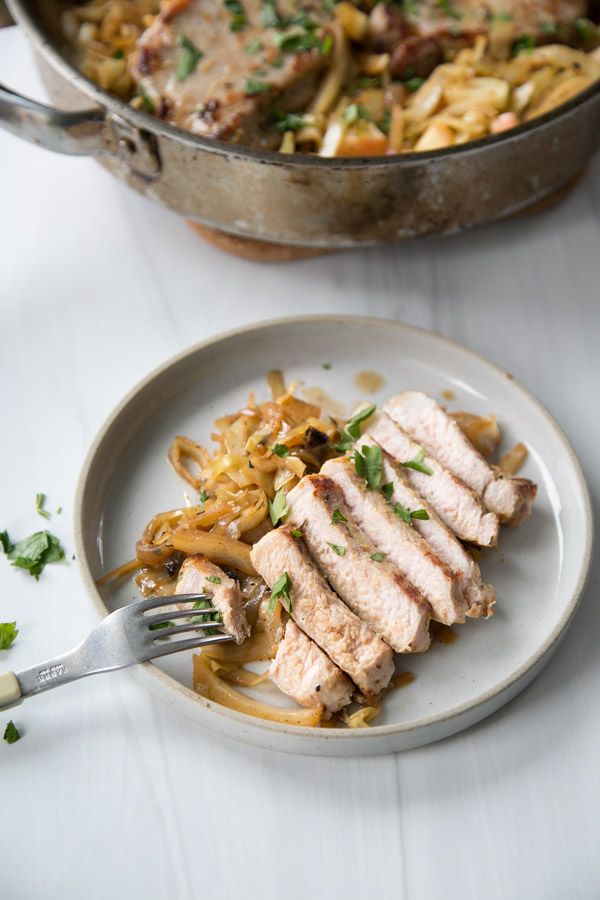 sliced pan fried boneless pork loin chops and cabbage on a plate with fork