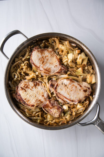 seared boneless pork loin chops in a skillet with cabbage