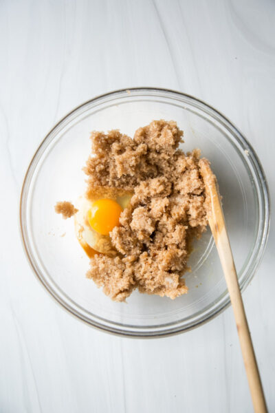 creamed coconut oil and sugar with raw egg in a bowl