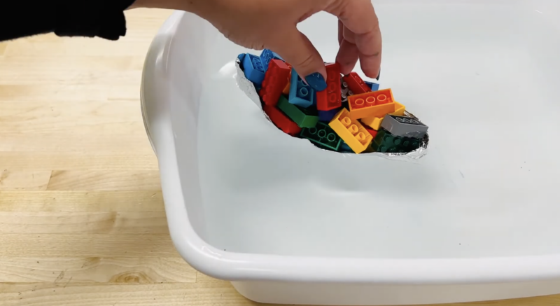 Preschool Science Experiments an image of an aluminum foil boat with legos in a small tub of water