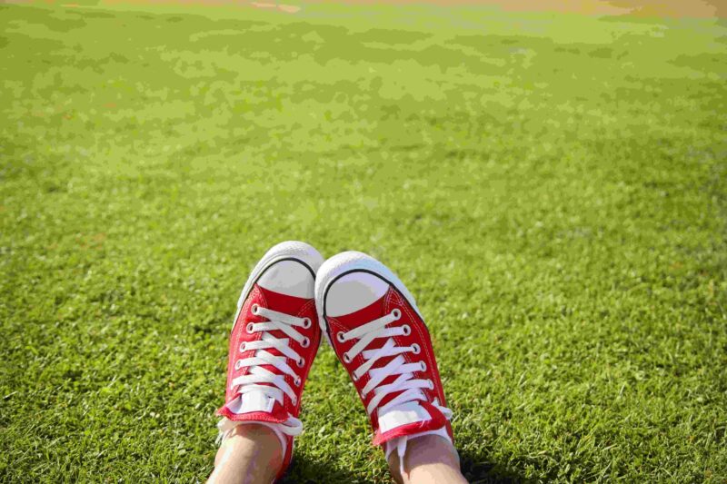 Feet in red sneakers in the green grass