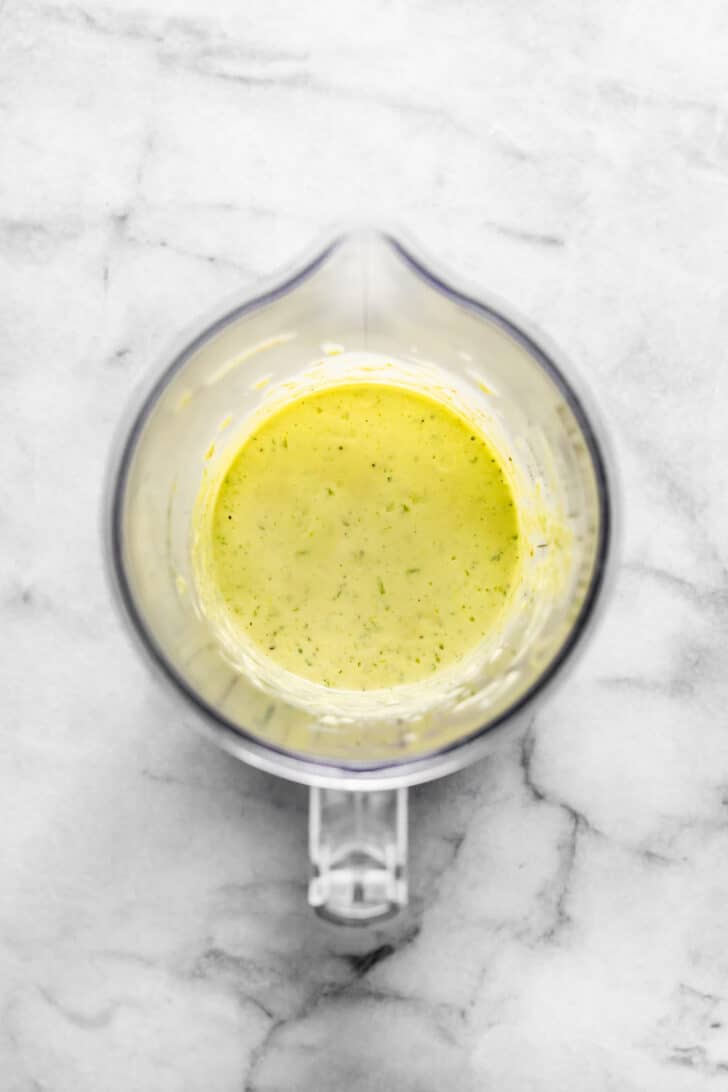Blended dressing in a small container, showing a smooth, pourable consistency with bits of herbs.