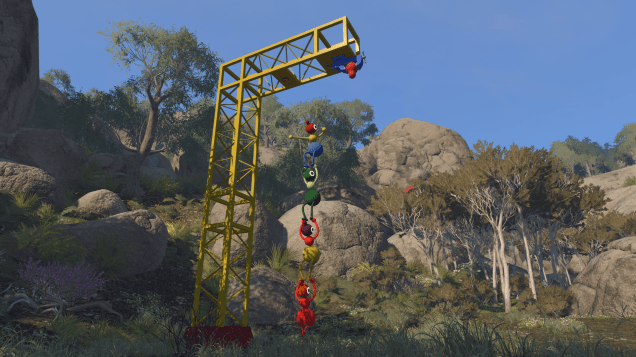 A group of four Big Walk player-characters stand on each other's shoulders in an attempt to reach the solution to a puzzle hanging from above them via yellow iron scaffolding.