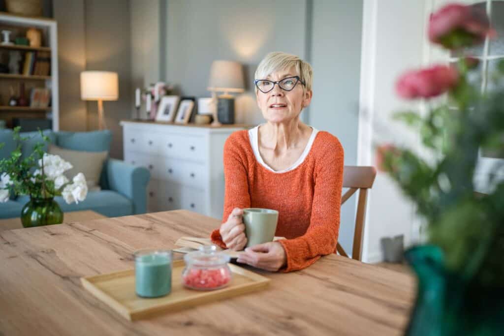 Older woman sitting at a dining table in a comfortable home.