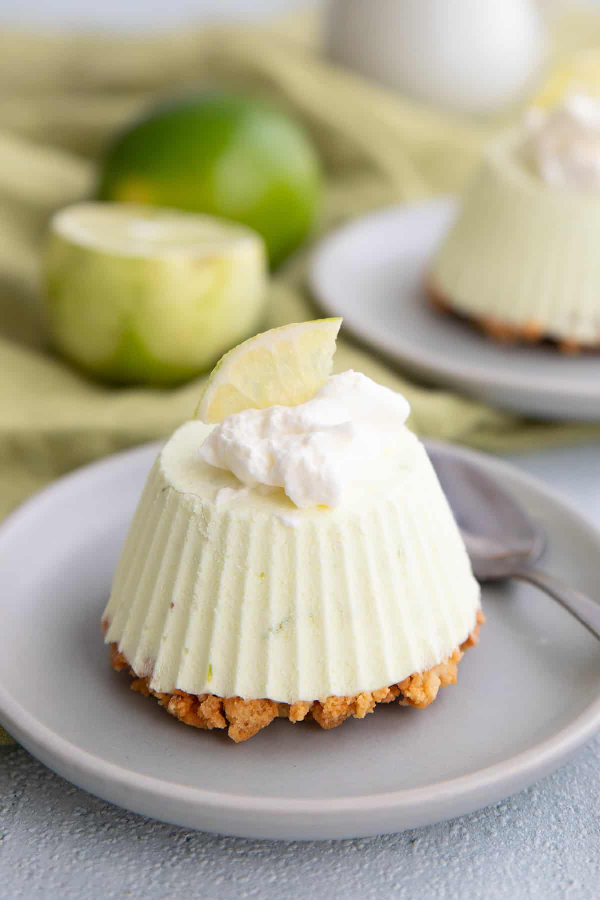 A Keto Frozen Key Lime Pie on a small gray plate with whipped cream and a lime slice on top.