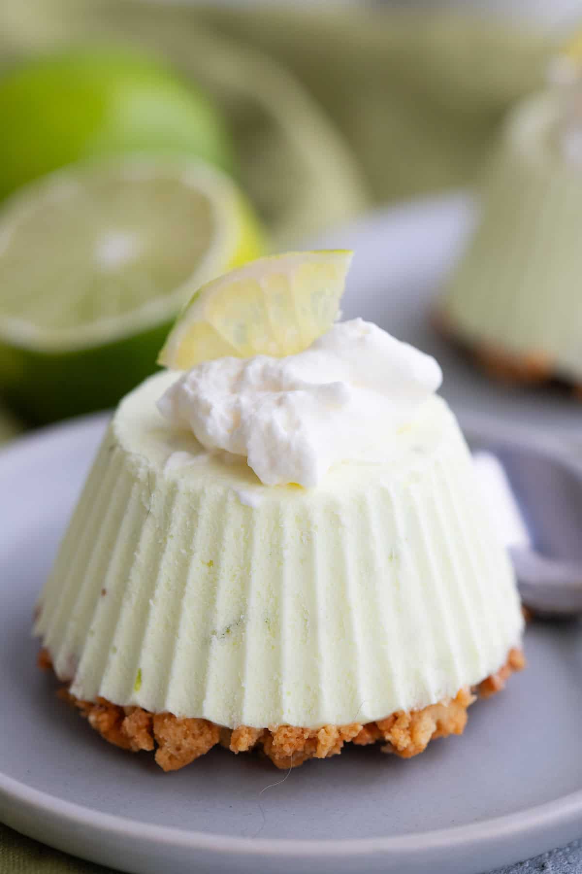Close up shot of a Keto Frozen Key Lime Pie on a small gray plate with whipped cream and a lime slice on top