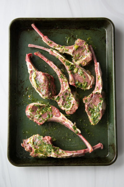 lamb chops marinating in mint sauce on a sheet pan