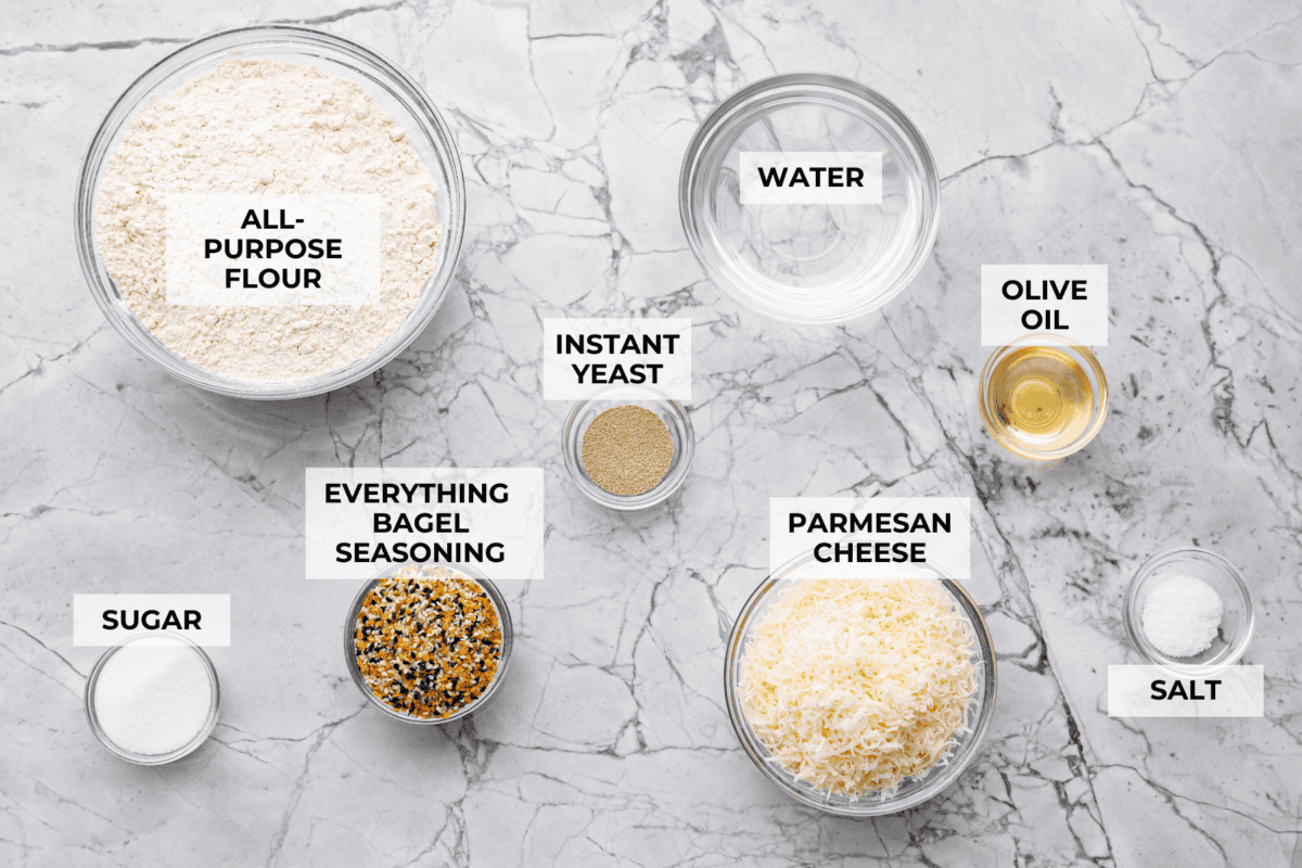 Overhead shot of labeled everything bagel pull apart bread ingredients. 