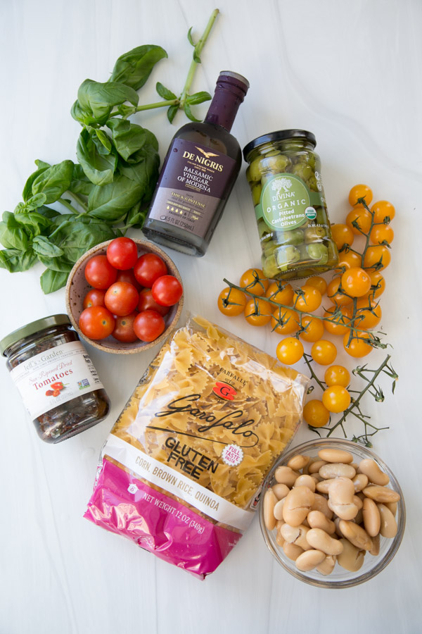 ingredients for gluten-free pasta salad on the counter - tomatoes olives balsamic basil beans
