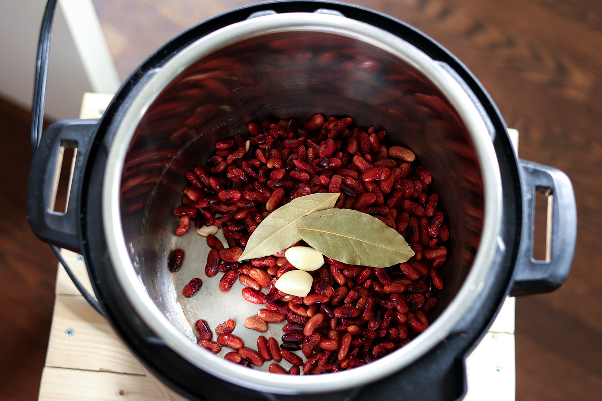 adding kidney. beans, garlic, and bay leaves to the Instant Pot