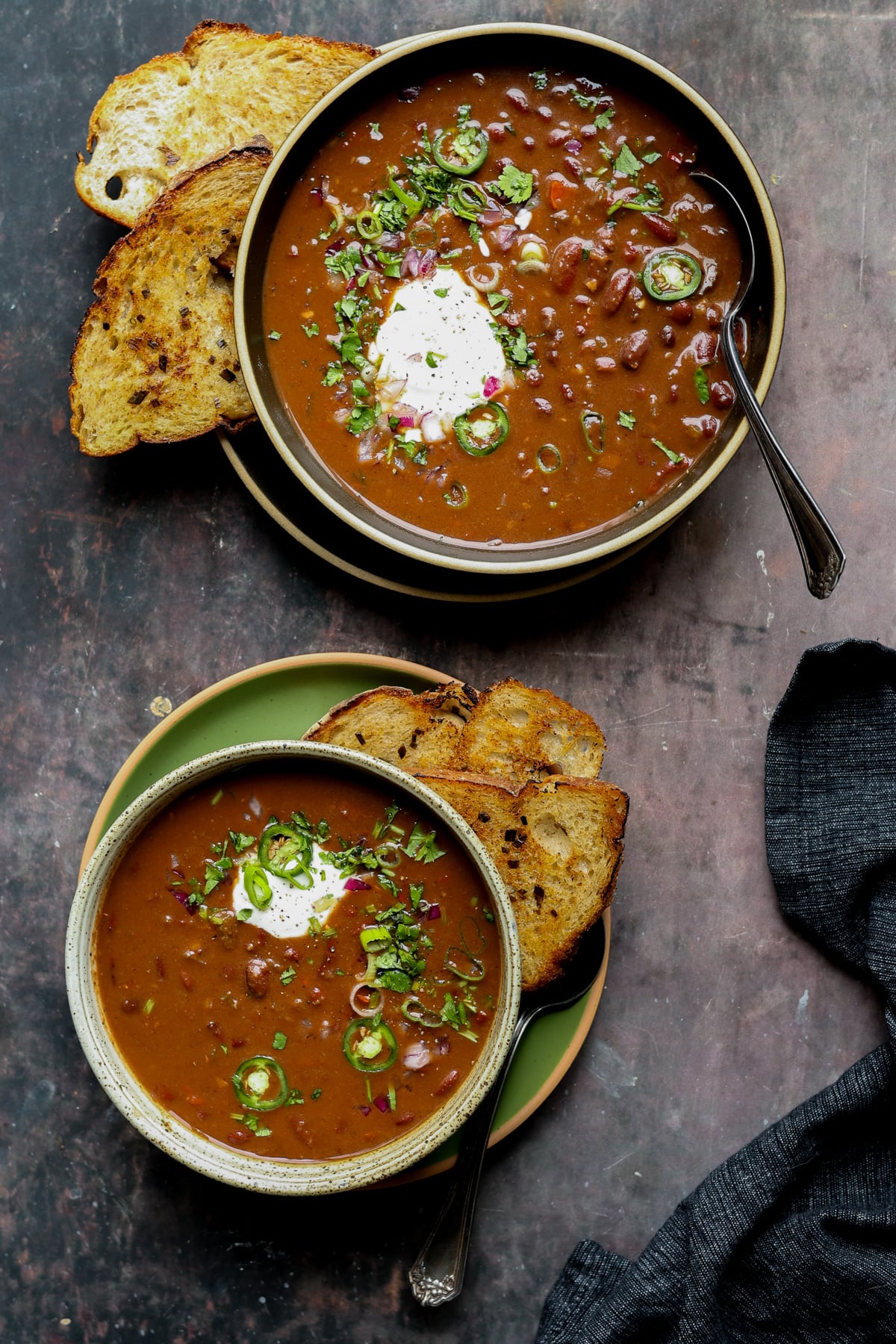 kidney bean chili in bowls with vegan sour cream and other toppings