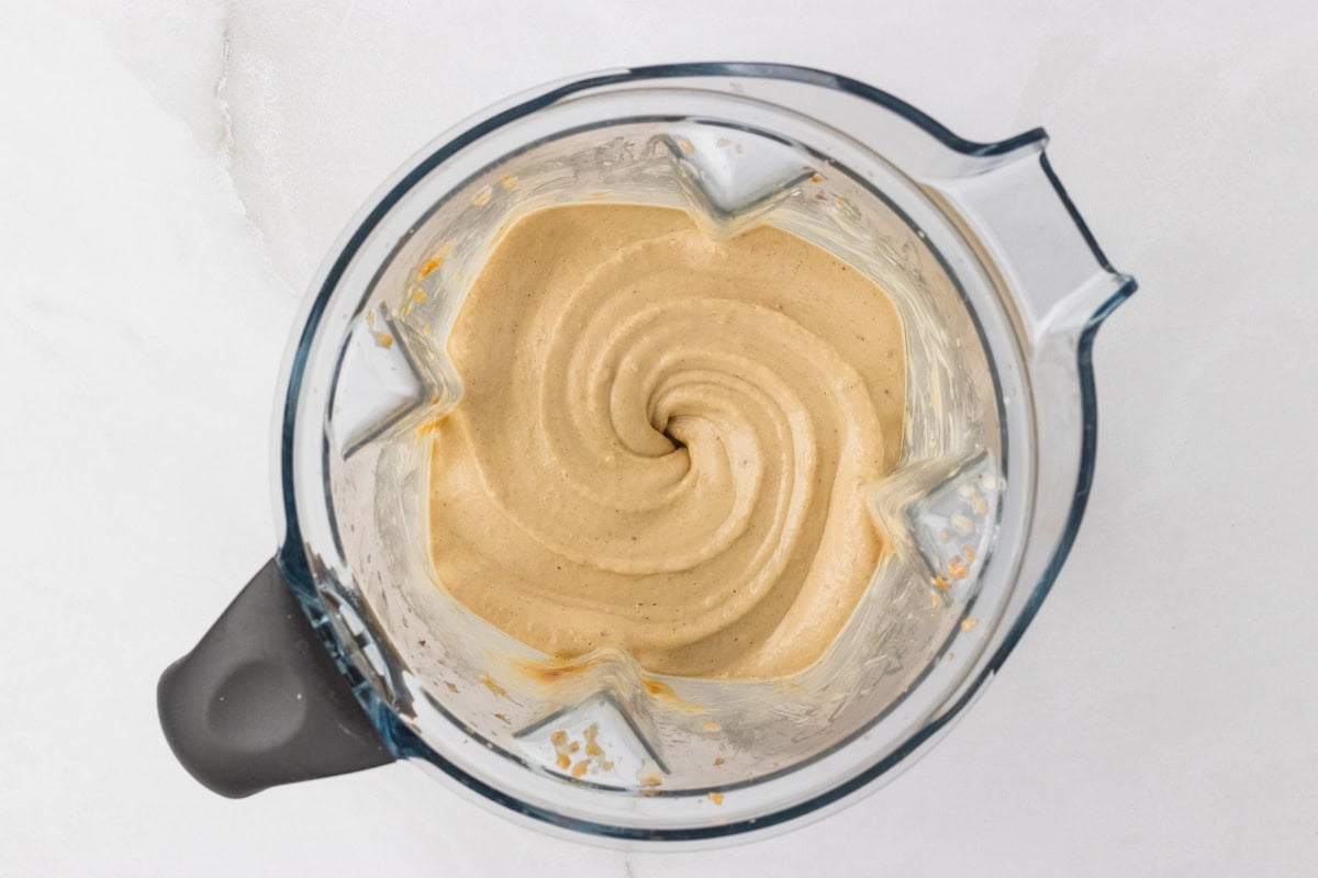 Overhead view of blended banana peanut butter nice cream mixture in a blender showing a thick, creamy swirl texture