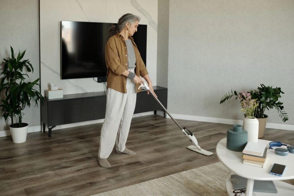 Older woman cleaning a living room floor with an easy-to-use mop.