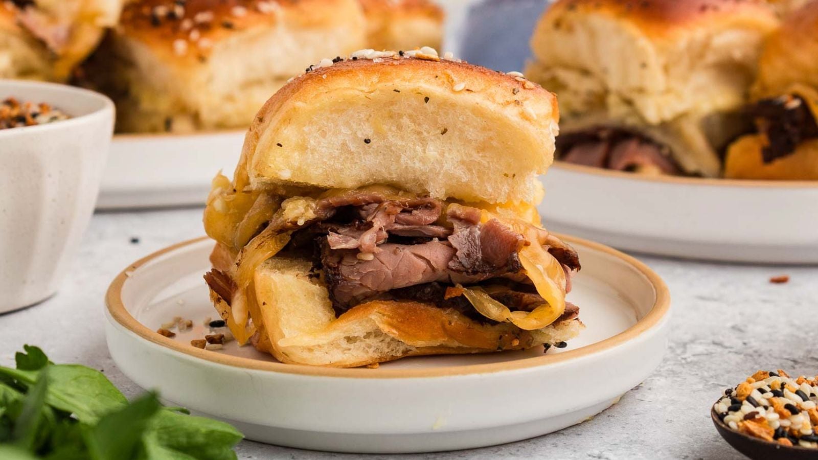 Roast beef sliders layered with horseradish sauce on toasted buns ready to serve.